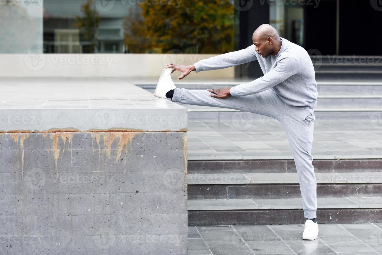 Black man doing stretching before running in urban background photo