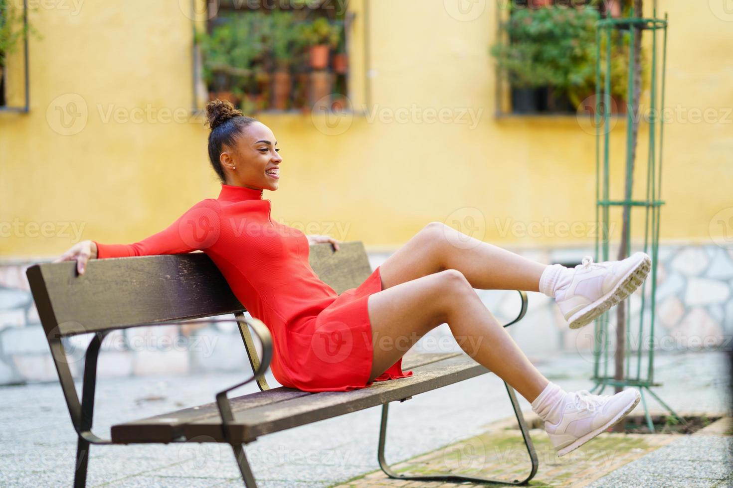 https://static.vecteezy.com/system/resources/previews/005/886/542/non_2x/happy-mixed-woman-moving-her-legs-in-joy-sitting-on-a-bench-in-the-street-photo.jpg