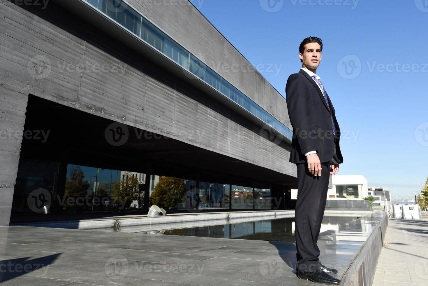 Young businessman wearing blue suit and tie in urban background photo