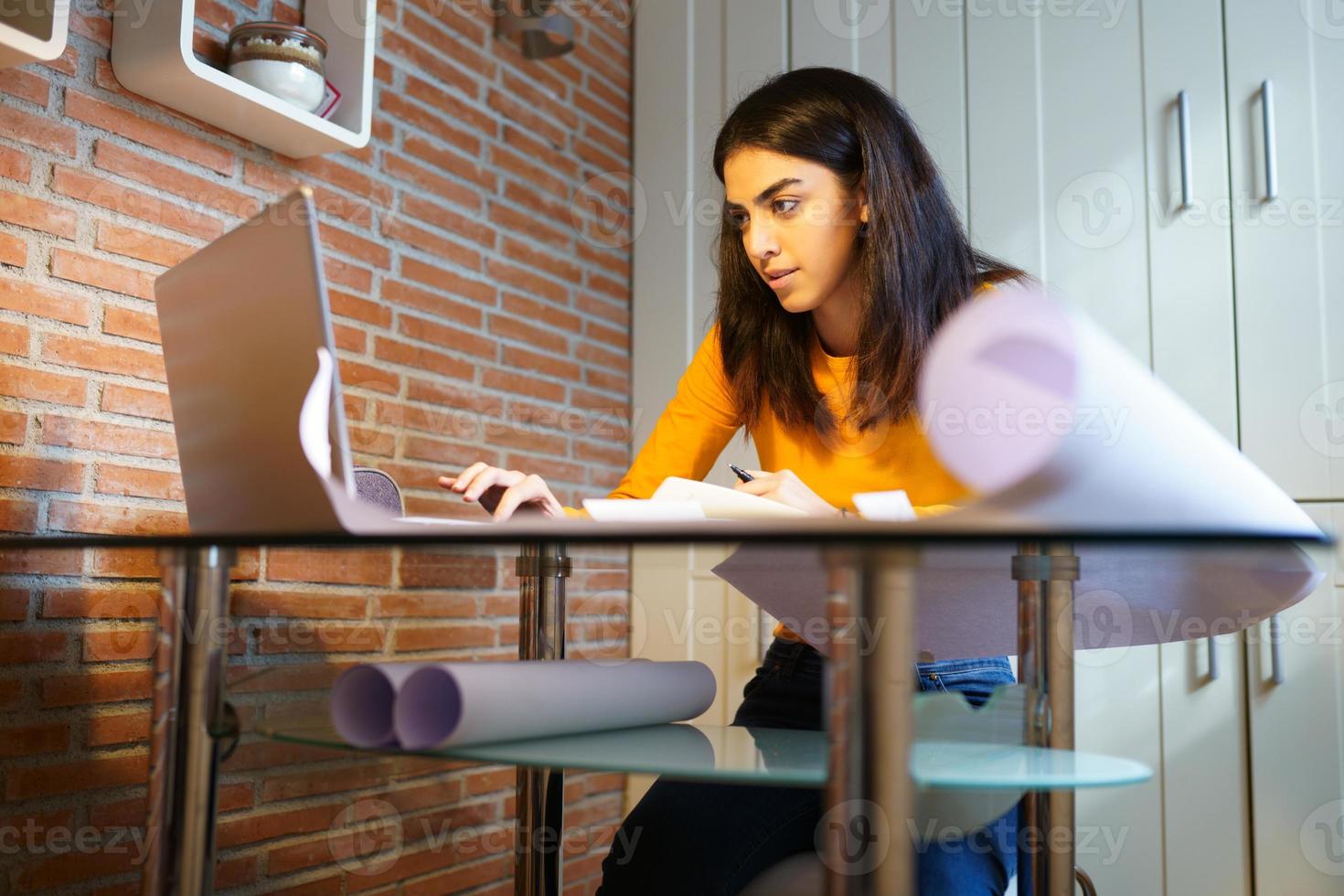 Female architect working at home with a laptop and blueprints photo