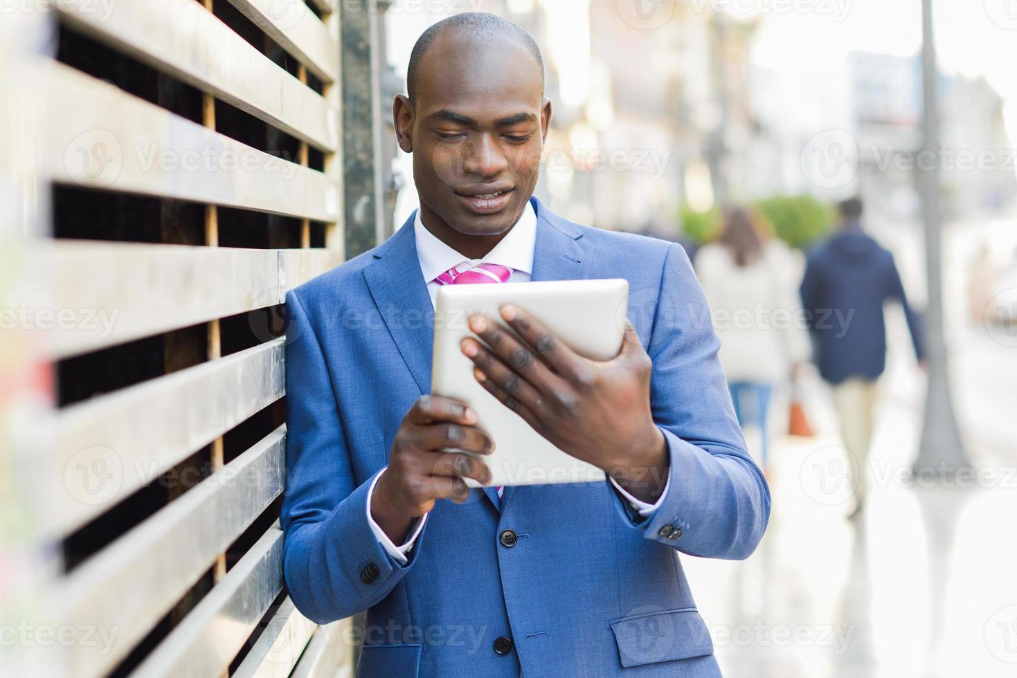 Black man wearing suit looking at his tablet computer photo