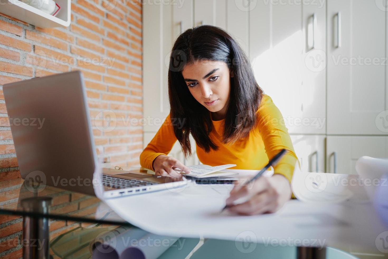 Female architect working at home with a laptop and blueprints photo