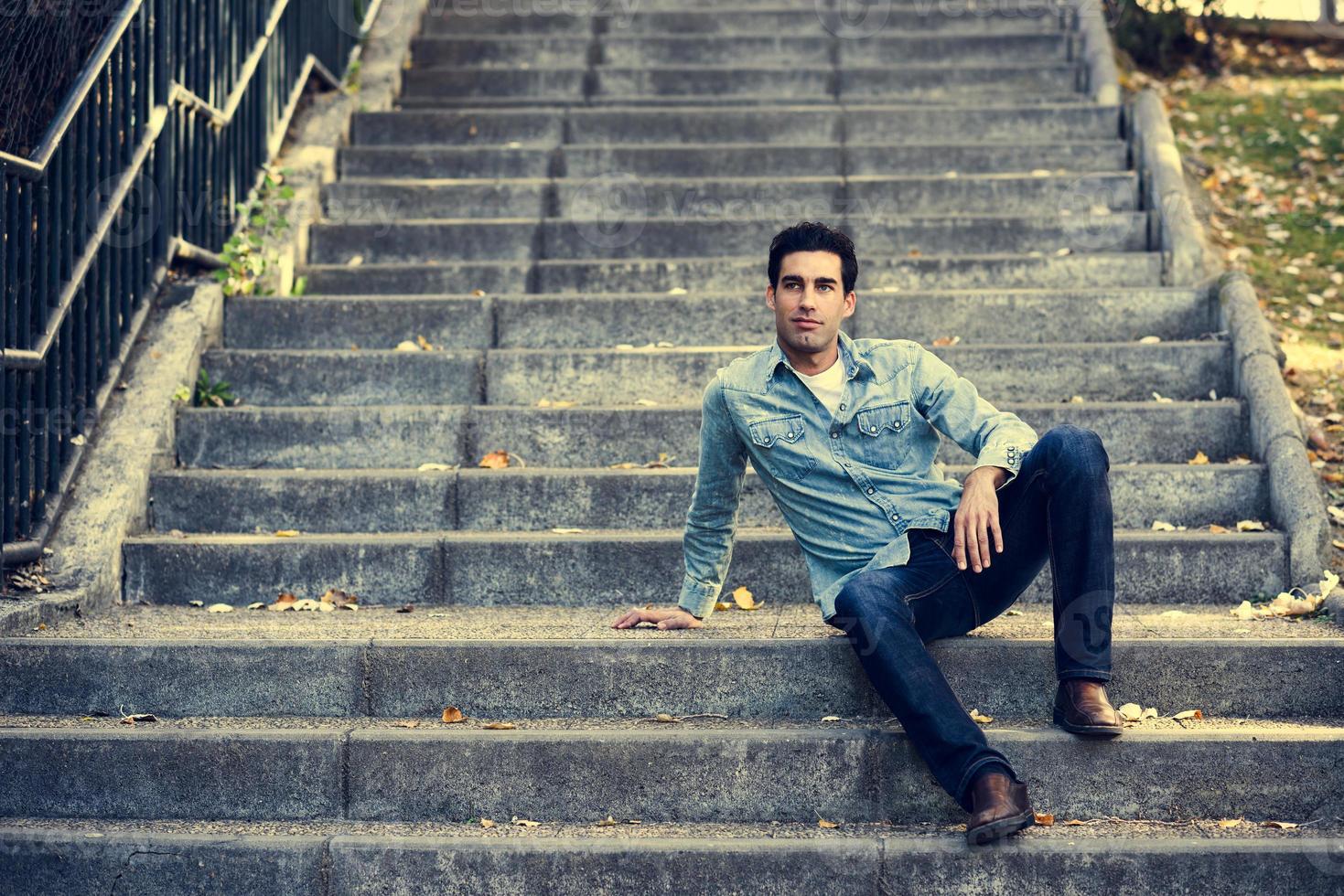 atractivo joven guapo, modelo de moda en el fondo urbano foto