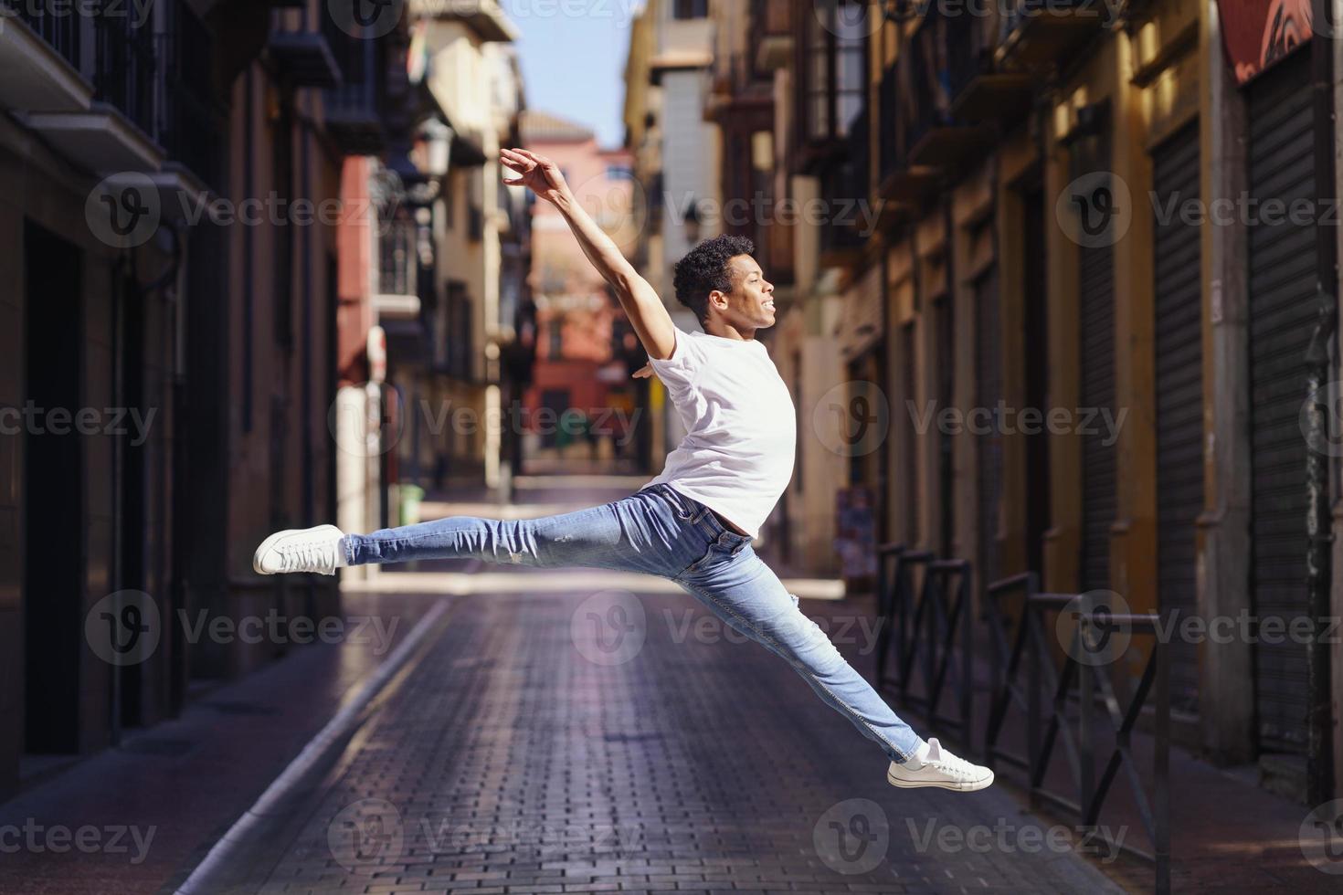 joven negro haciendo un salto acrobático en medio de la calle. foto