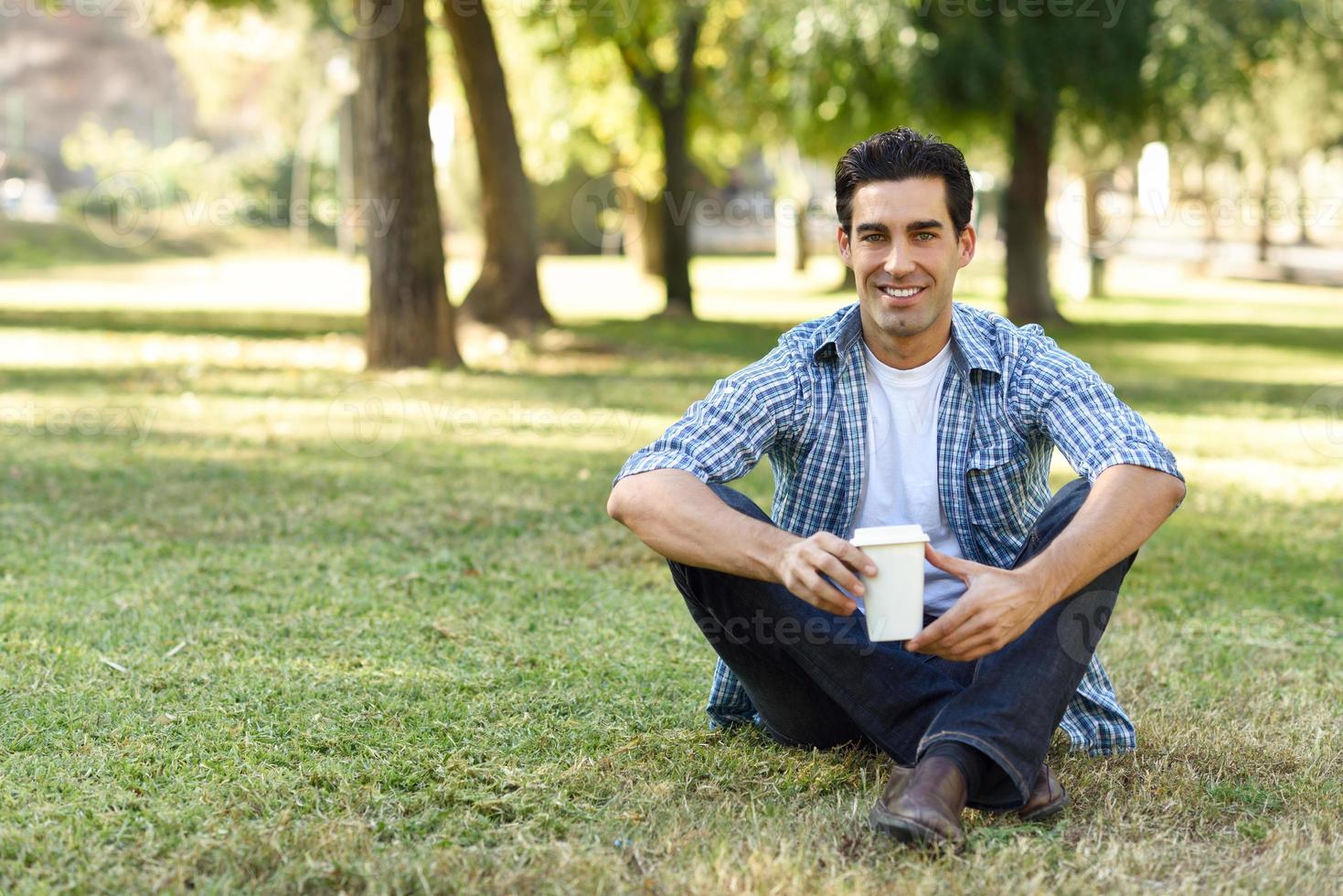 hombre bebiendo café para ir a un parque urbano foto