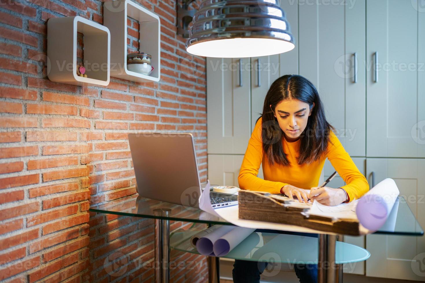 Female architect working at home with a laptop and blueprints photo