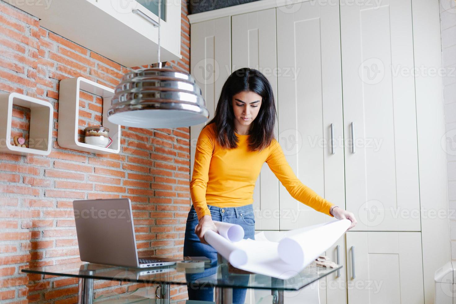 Female architect working at home with a laptop and blueprints photo