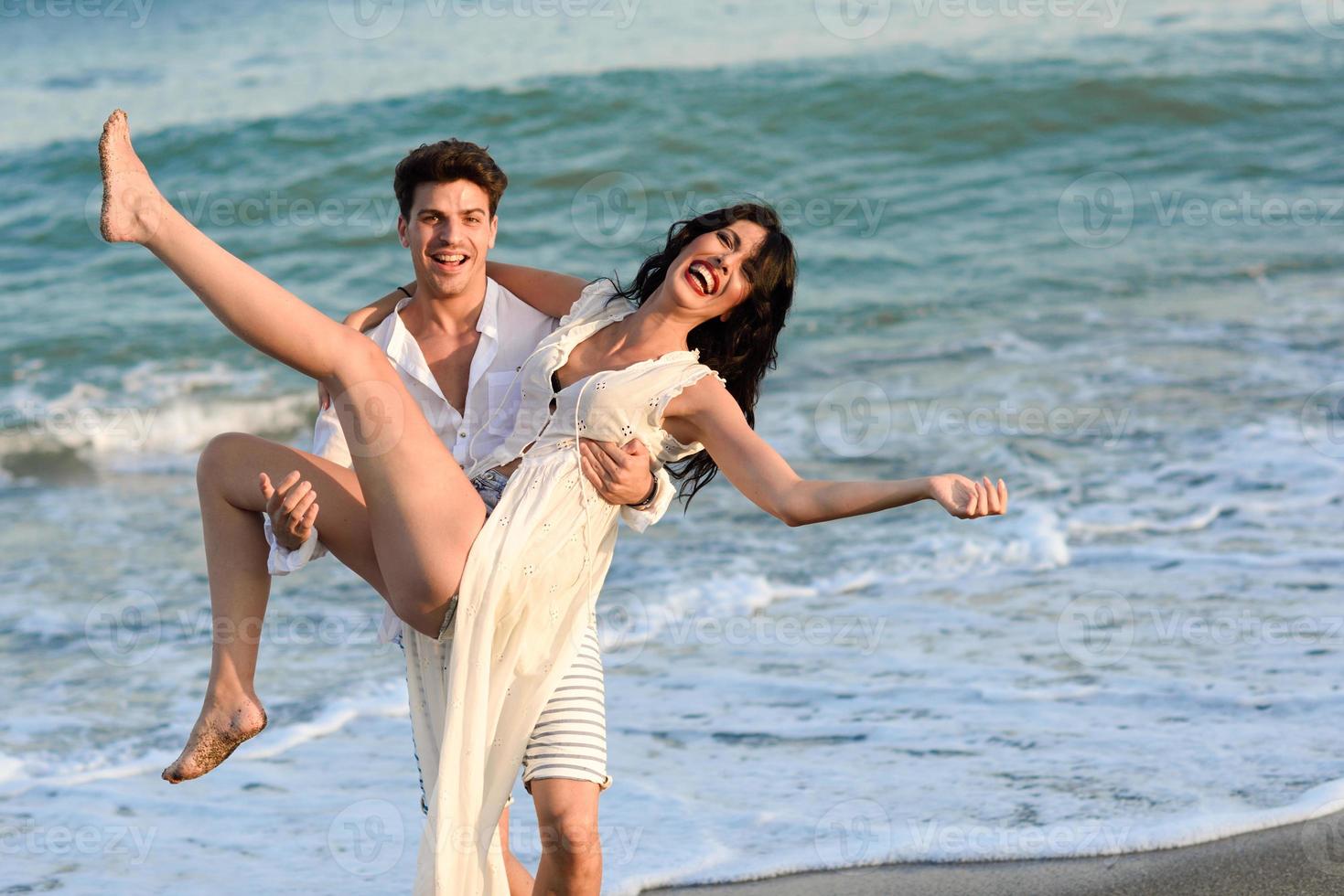 joven pareja feliz caminando en una hermosa playa foto