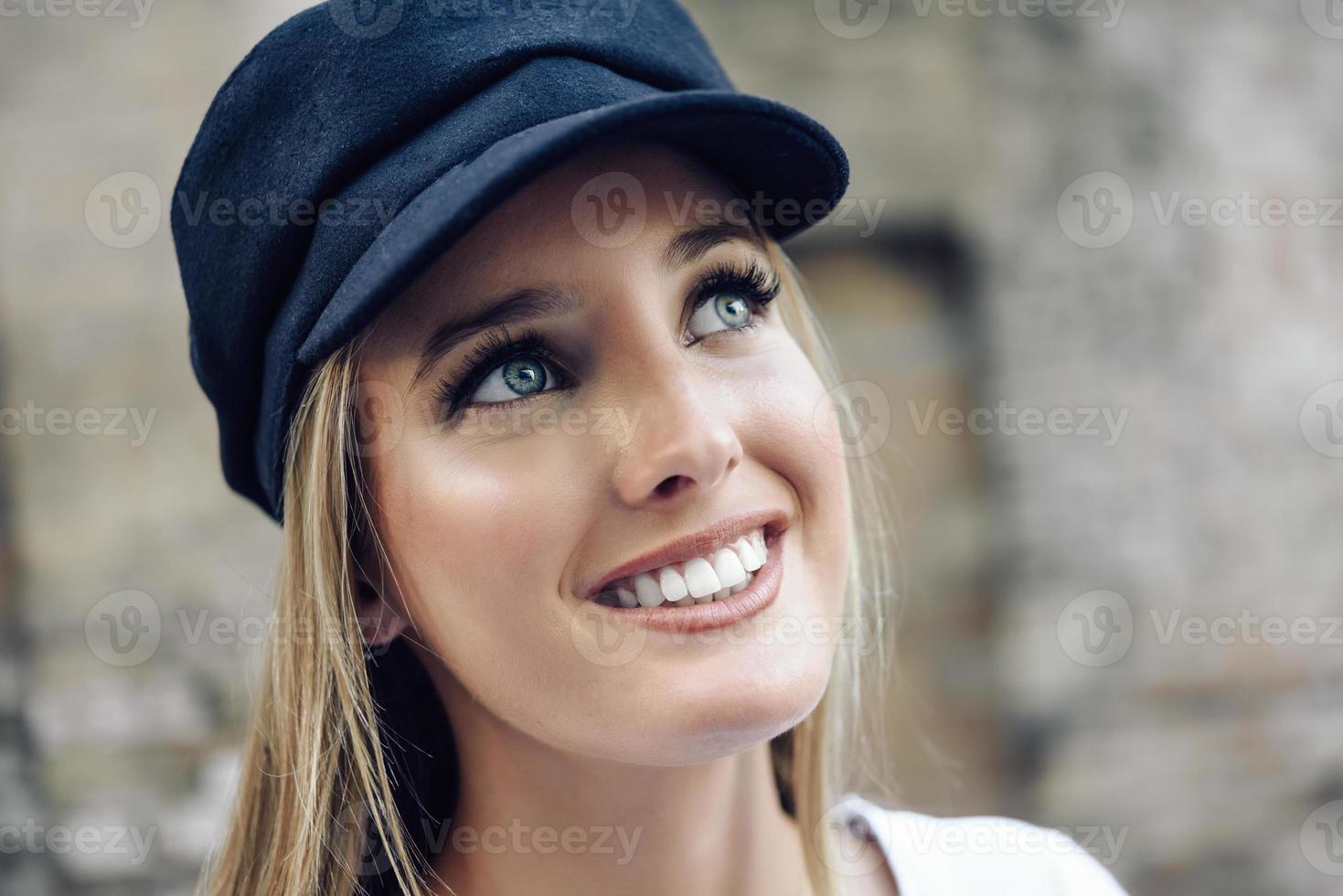 joven mujer rubia con gorra de fondo urbano. foto