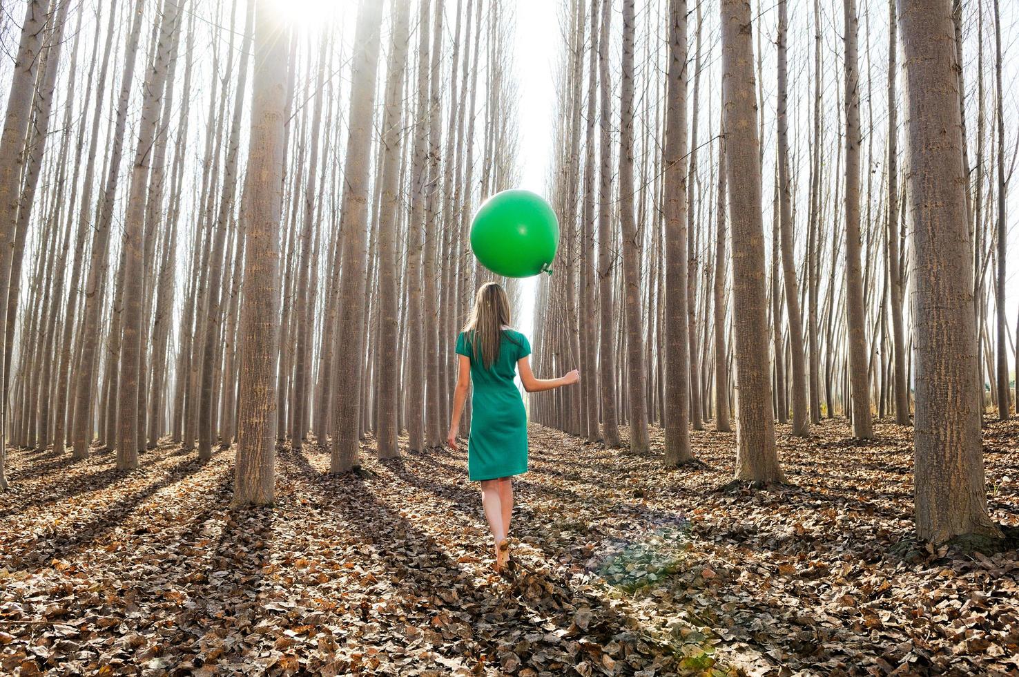 Beautiful blonde girl, dressed in green, walking into the forest photo