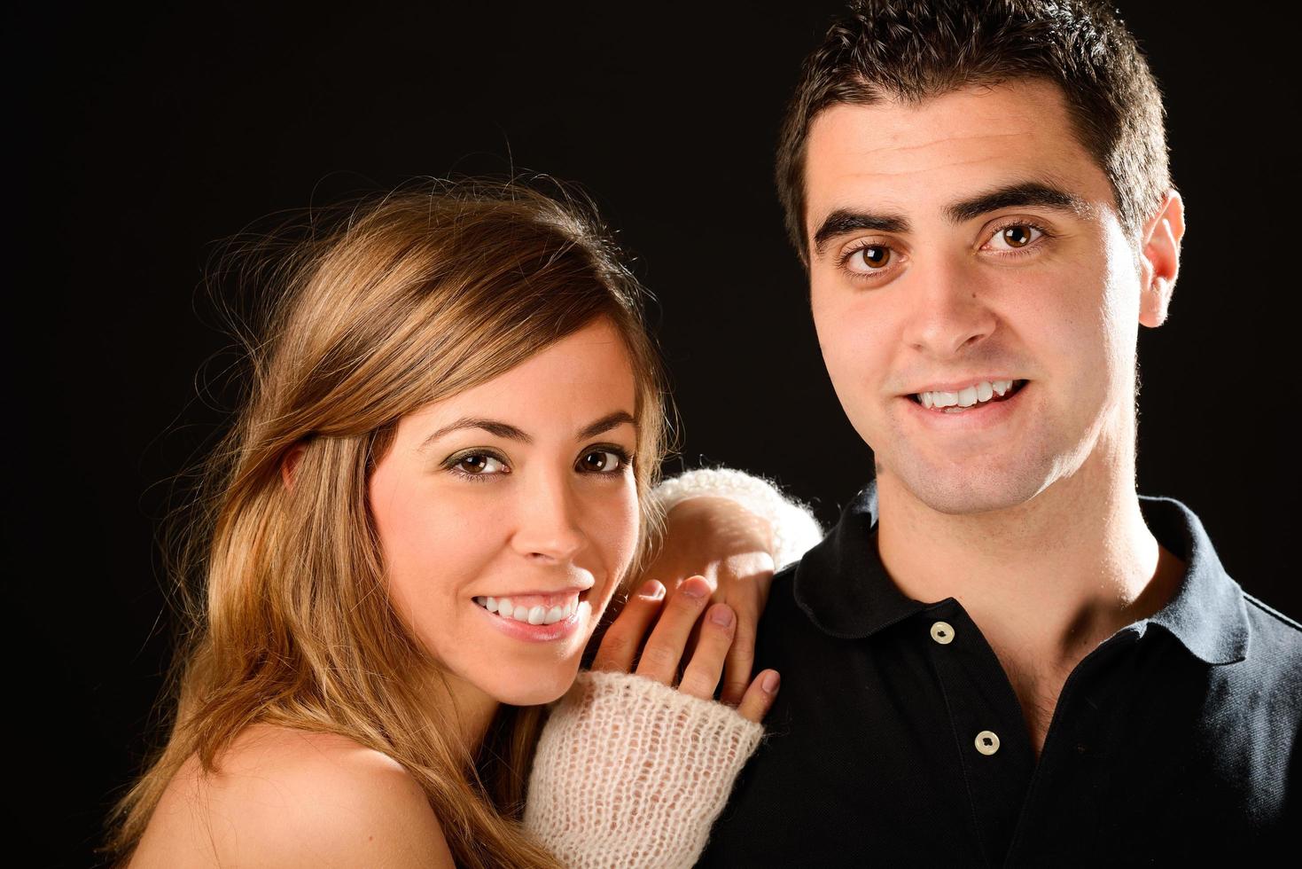 feliz pareja sonriendo a la cámara sobre fondo negro foto