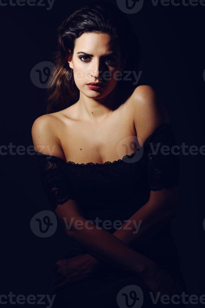 Young brunette woman in black lingerie in chiaroscuro lighting photo
