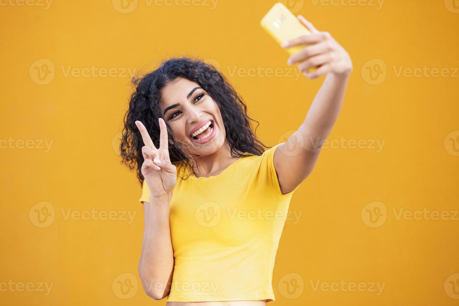 Young Arab woman taking selfie photograph with smartphone. photo