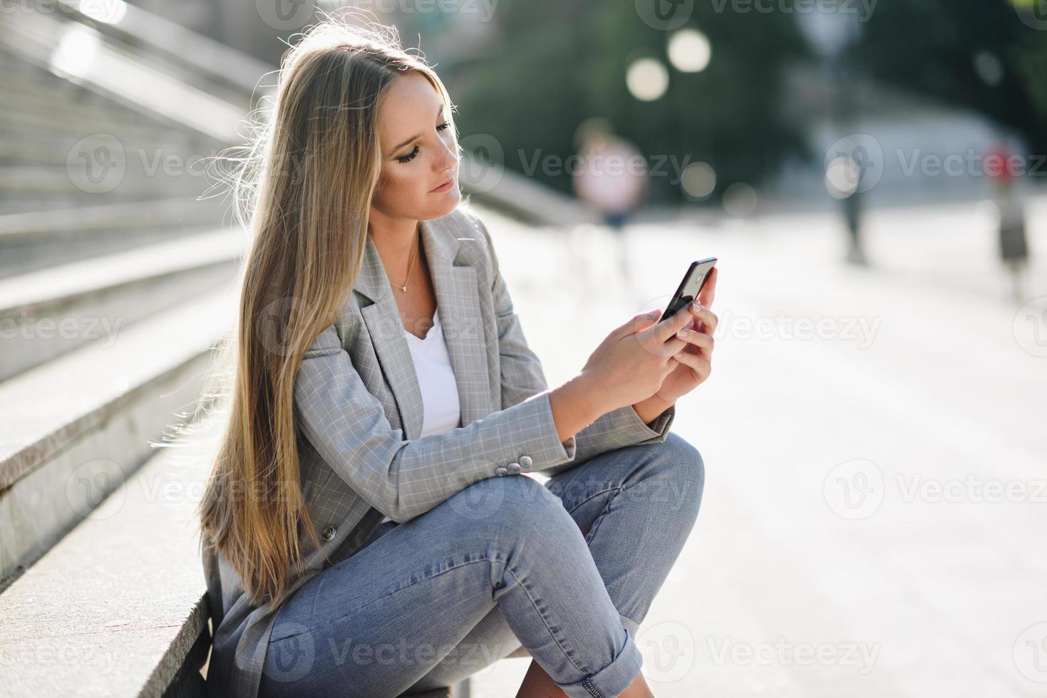 hermosa joven rubia mirando su teléfono inteligente. foto