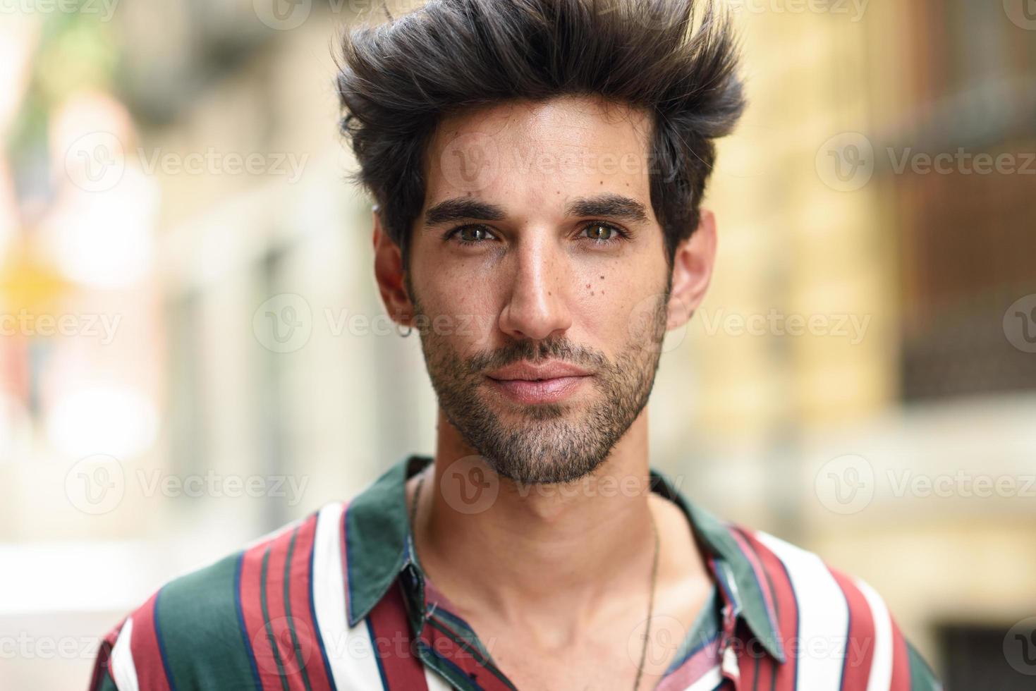 joven atractivo con cabello oscuro y peinado moderno con ropa informal al aire libre foto