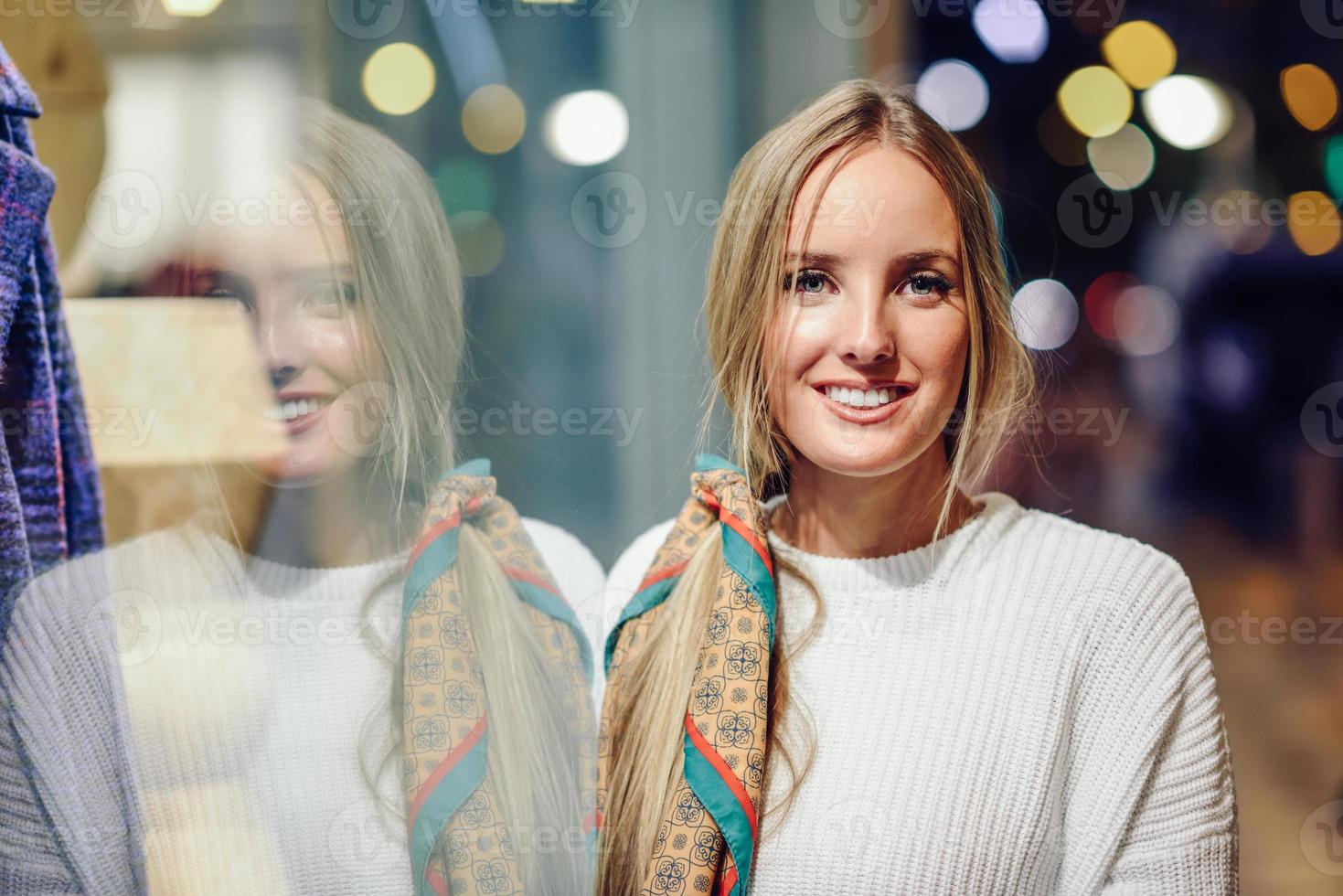 Blonde girl smiling with defocused urban city lights at night photo