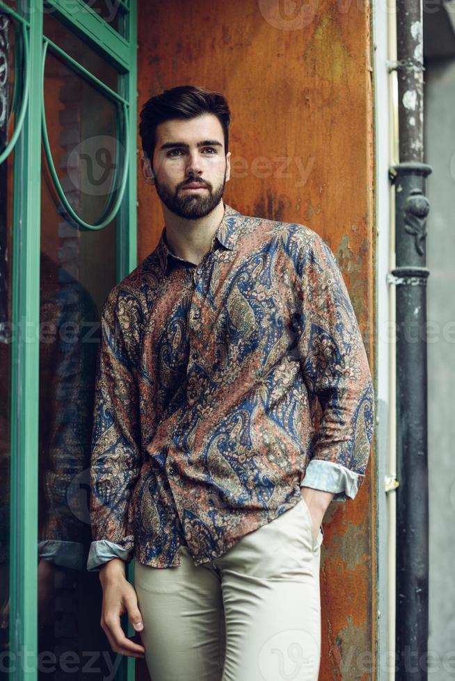 Young bearded man, model of fashion, wearing shirt in urban background. photo