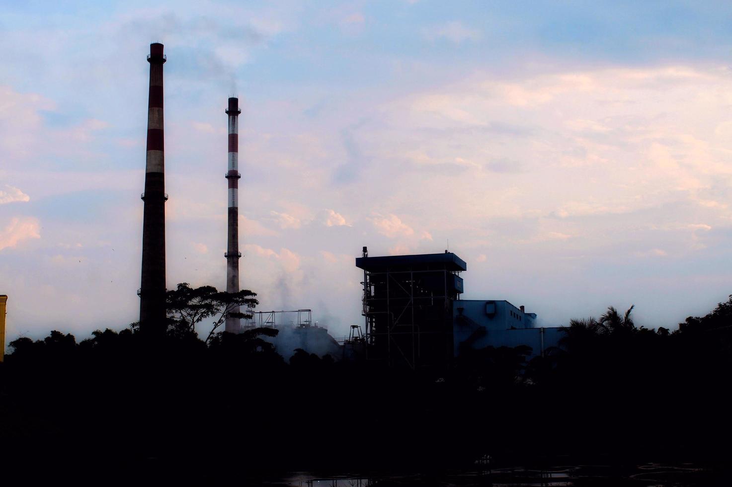 Silhouette photo of a power plant showing tall chimneys