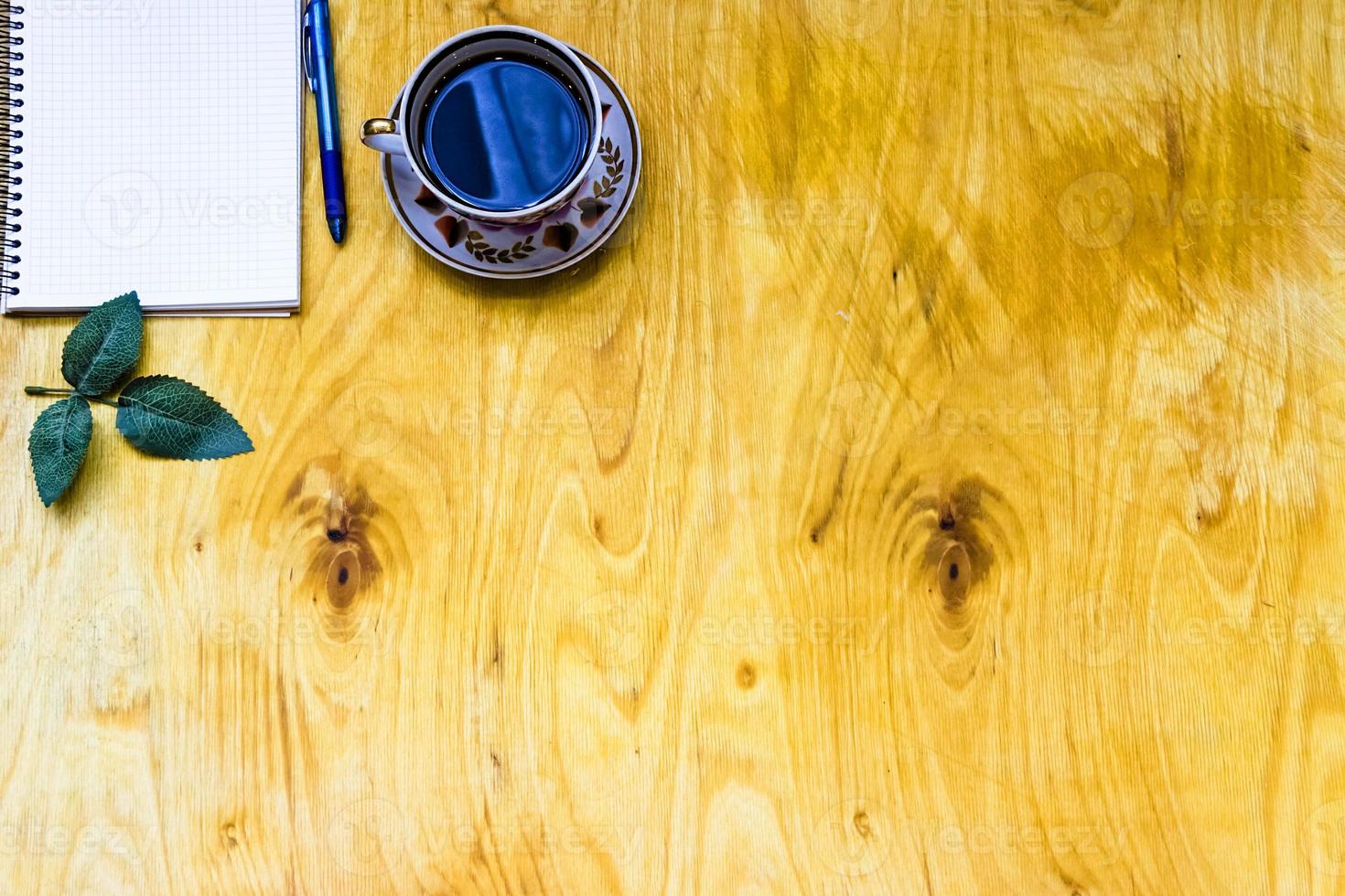 Cup of coffe and open notebook on wooden background photo