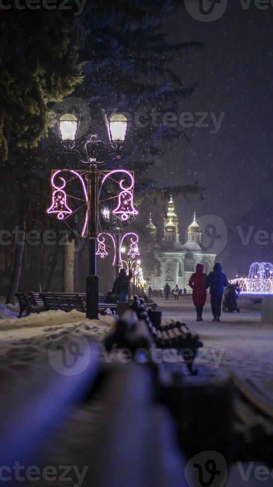 Close up photo of a street lamp in the dark in winter with falling snowflakes. Street decorated for Christmas and New Year. Evening magical atmosphere. Street at night. Street retro lighting.