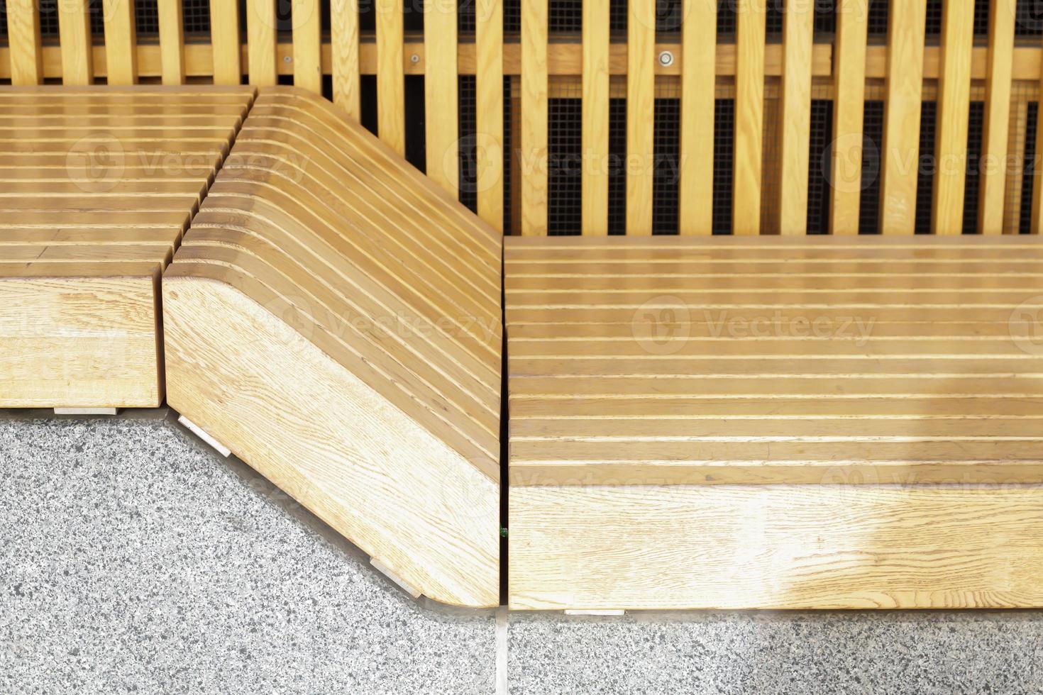 Empty modern wooden benches without people on a sunny day, public places in the city park. City improvement, urban planning, public spaces, recreation area. City public anti-vandal furniture for rest. photo