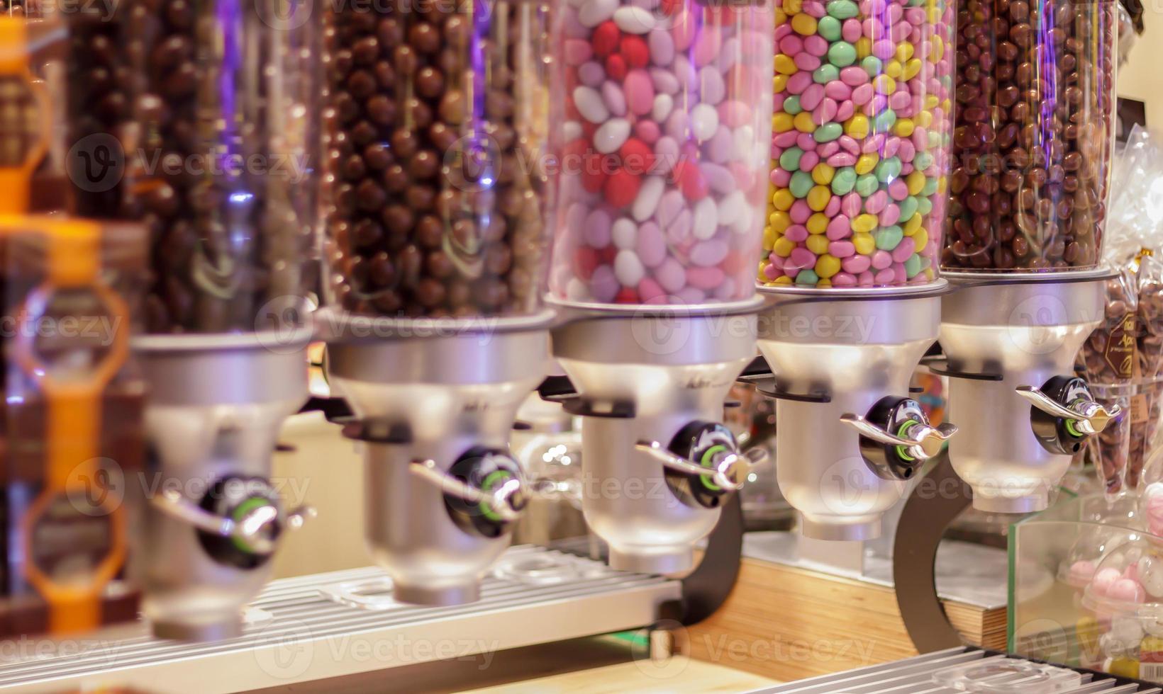 Colorful variety of fruit candies in plastic tubes in a candy store. Jelly beans for sale in the store. Colorful chewing gum balls in a pastry machine. Selective focus. photo