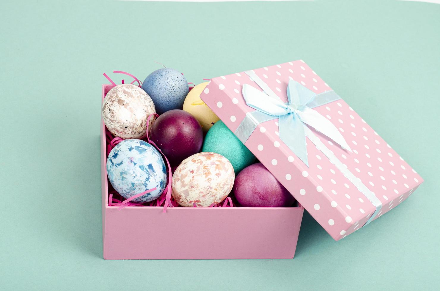 Multicolored eggs in open gift box. Concept of the Happy Easter holiday, greeting card template. Studio Photo