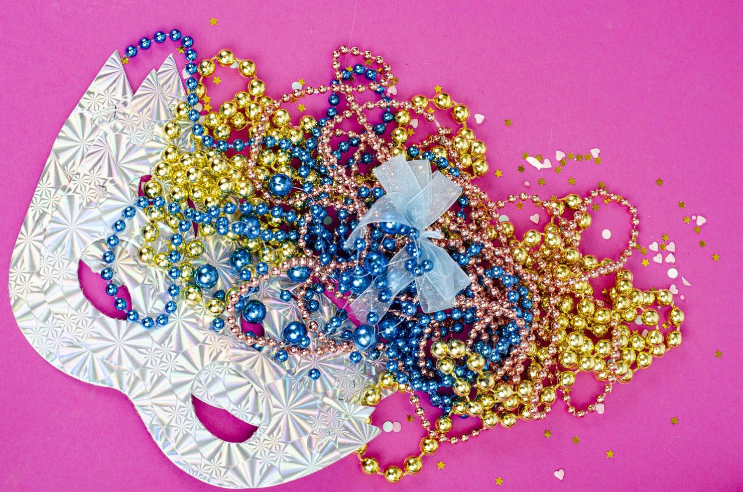 Color mardi gras beads, masks on bright background. Studio Photo