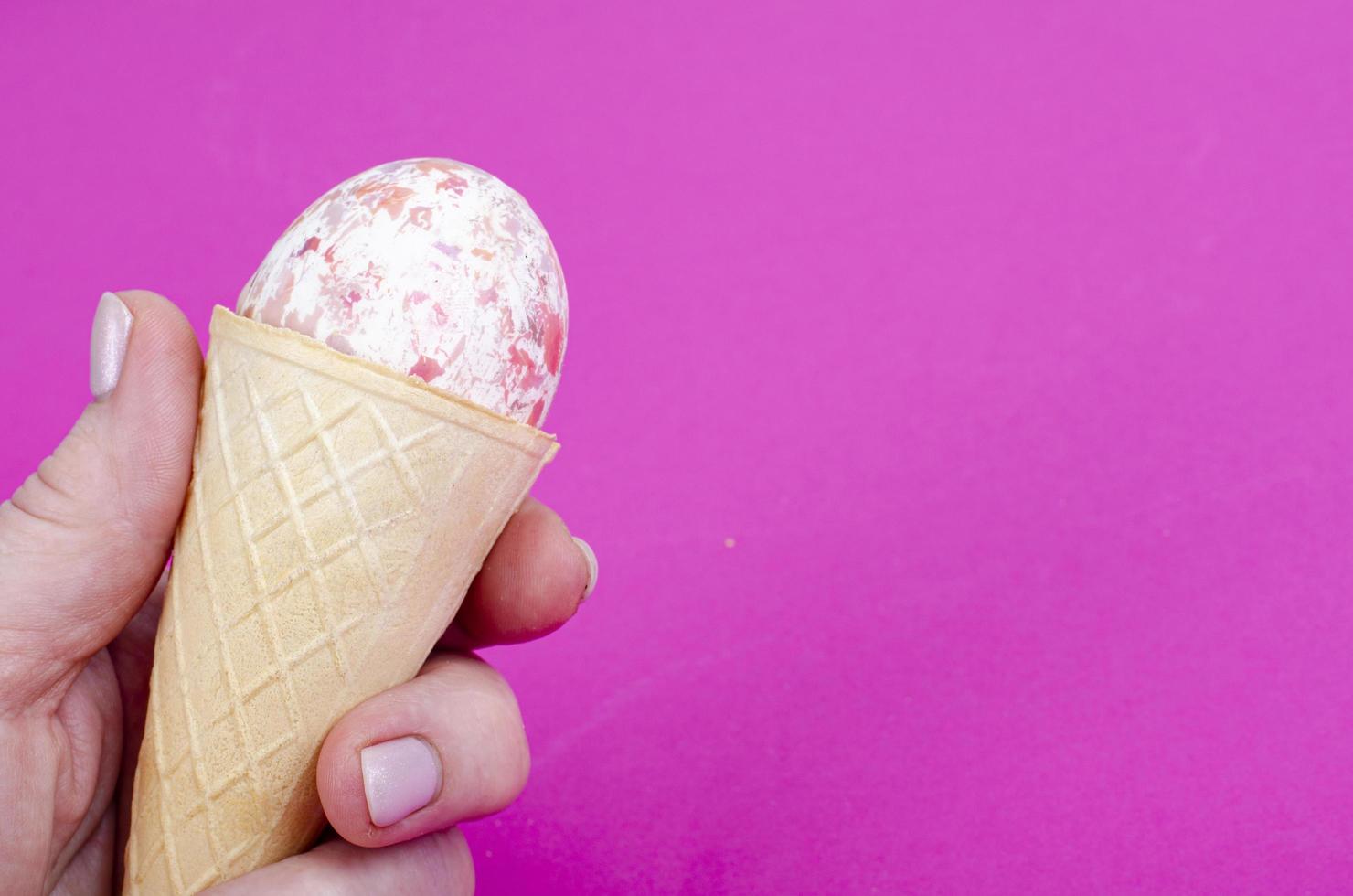 Vanilla ice cream waffle horns with decoration eggs on pink background. Minimalism. Creative Easter concept. Studio Photo