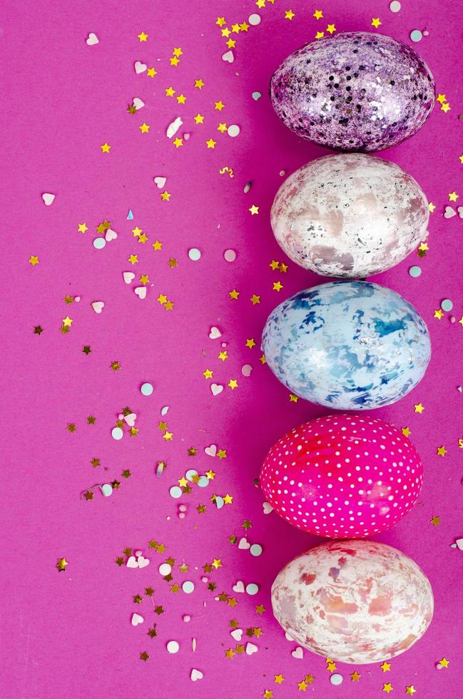 Multicolored handmade easter eggs and confetti on pink background. Minimal concept. View from above. Space for text. Studio Photo