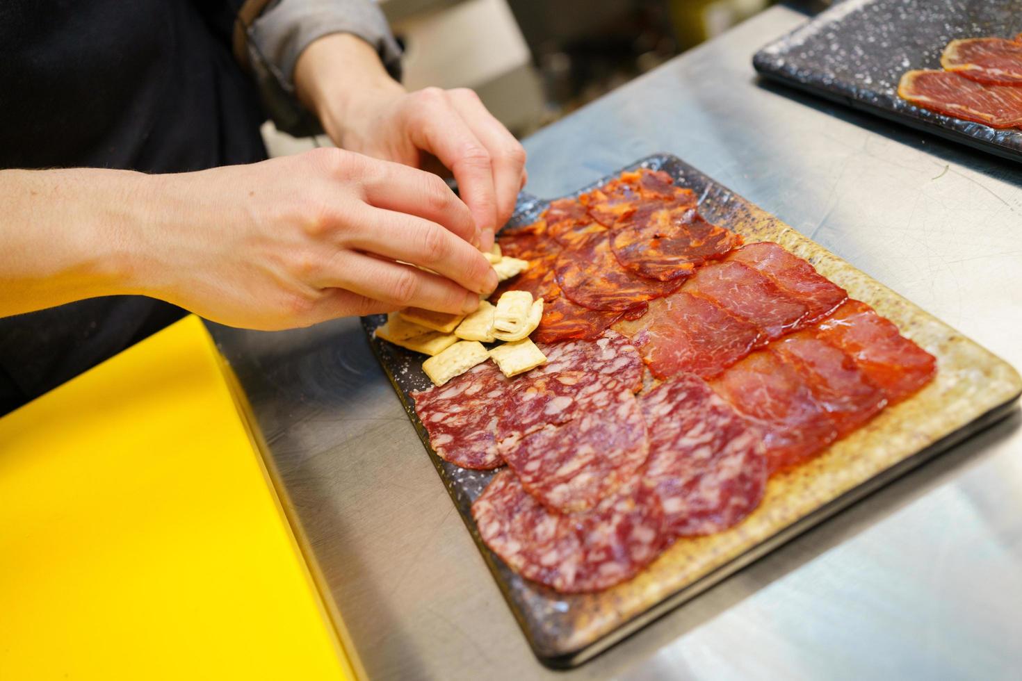 Unrecognizable chef preparing a plate of Iberian cured meats platter. photo