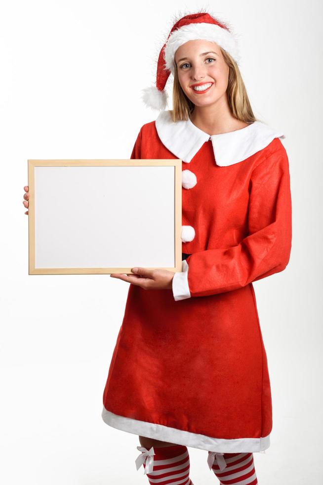 Smiling blonde woman in Santa Claus clothes with white board photo