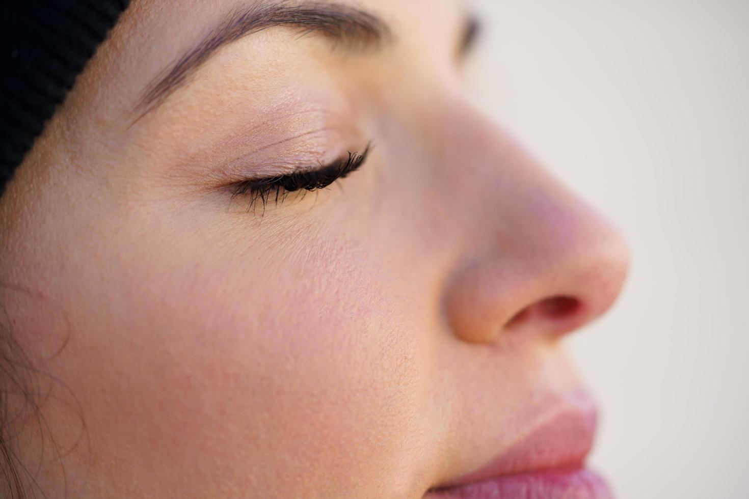 Closed portrait of young woman leaning against a wallwith her eyes closed. photo