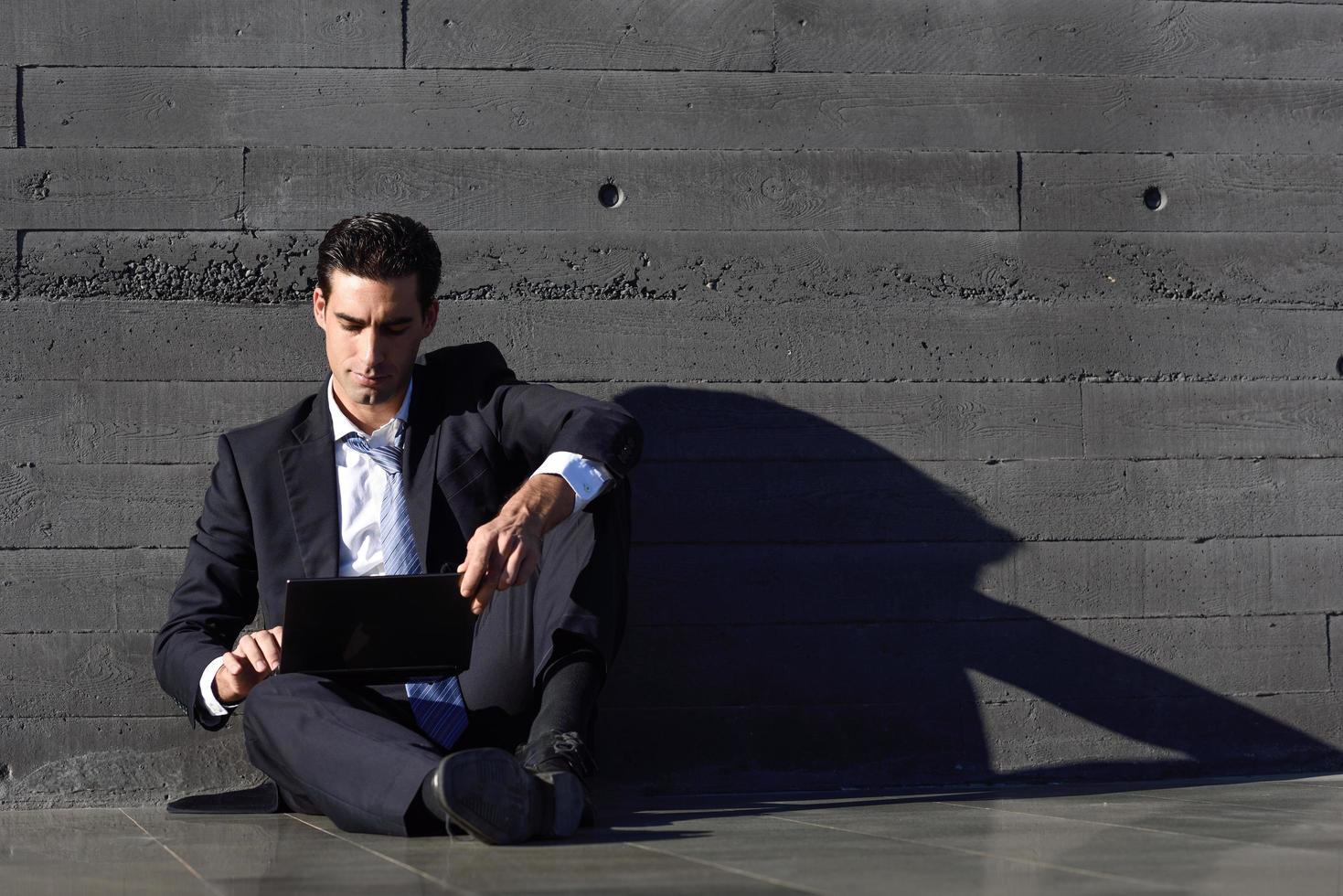 Businessman using a laptop computer sitting in the street photo