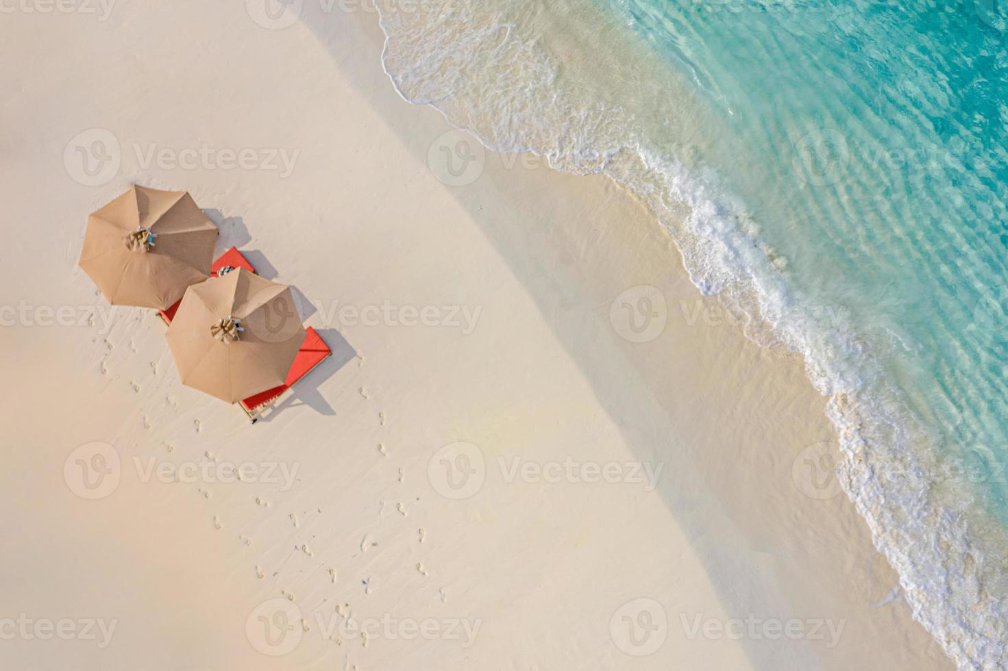 Aerial view of amazing beach with umbrellas and lounge chairs beds close to turquoise sea. Top view of summer beach landscape, idyllic inspirational couple vacation, romantic holiday. Freedom travel photo