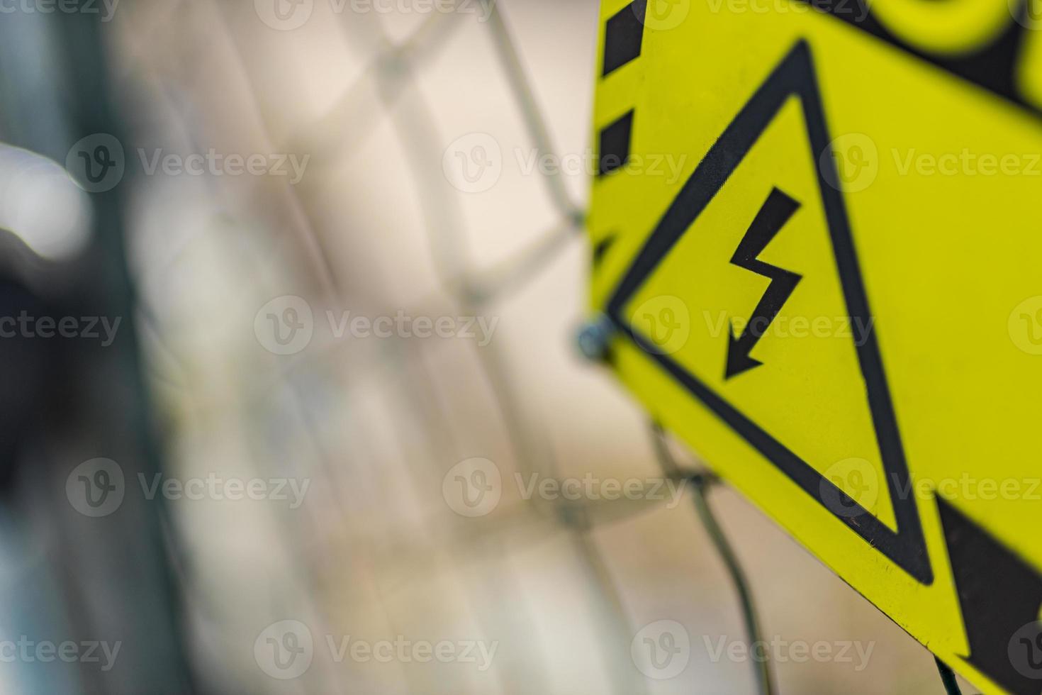 Danger high voltage sign isolated from blurred metal fence background. Abstract dangerous environment background, warning signs photo