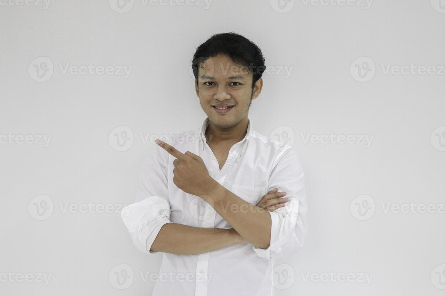 sonrisa de un joven asiático con camisa blanca y punto de mano en el espacio vacío foto