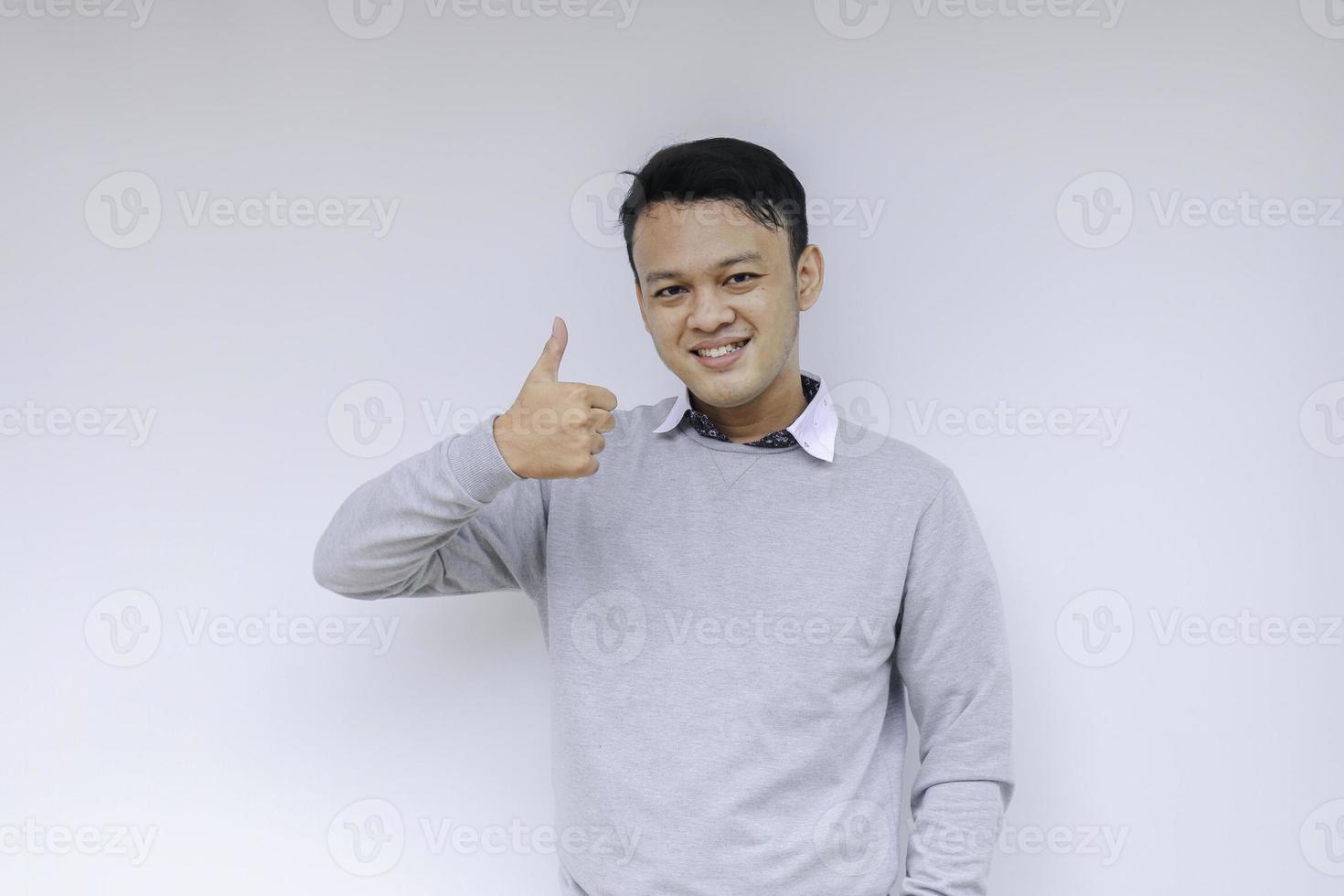 joven asiático usa camisa gris con cara sonriente feliz y pulgar hacia arriba o signo ok foto