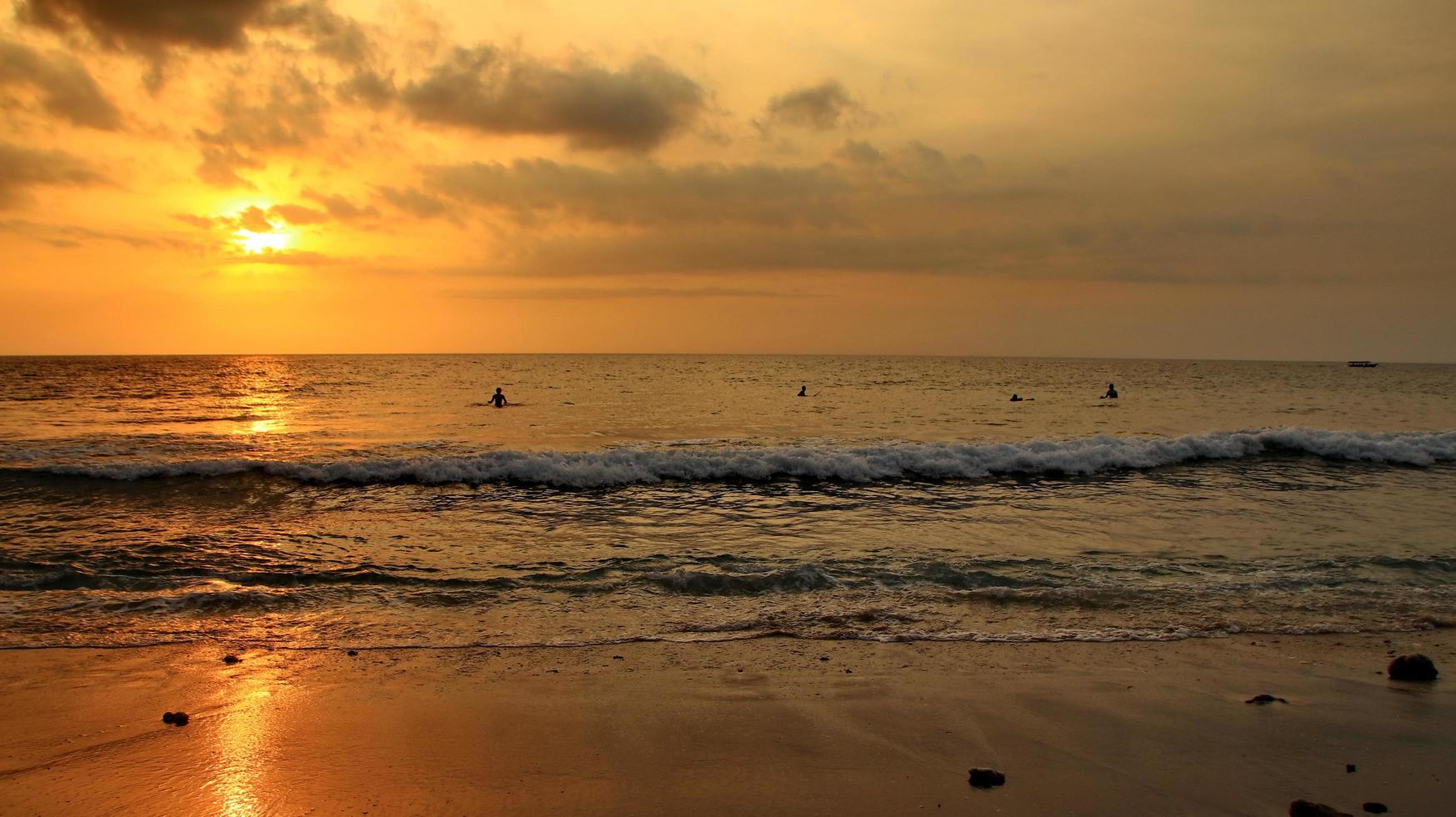 Documentation of surfers in action at dusk with a golden color and dark, unfocused and dark on the beach of Senggigi Lombok, West Nusa Tenggara Indonesia, 27 November 2019 photo