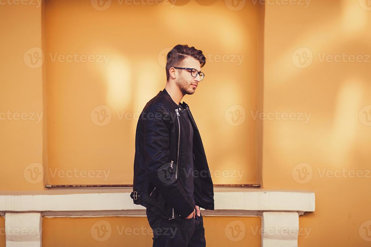 man in leather jacket standing near colorful wall photo