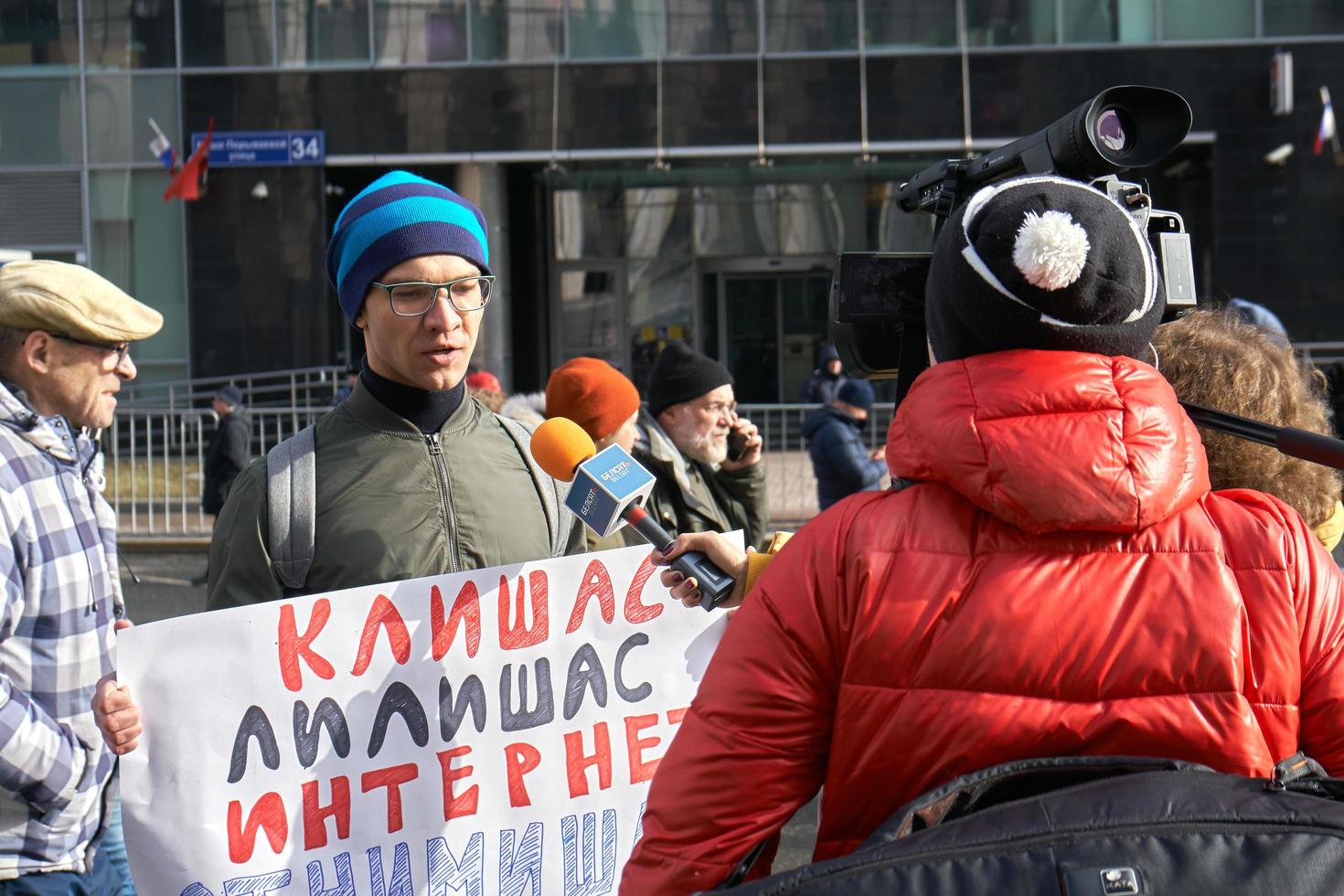 Moscow, Russia - March 10, 2019. Female TV reporter interviewing a young demonstrator holding a political banner photo