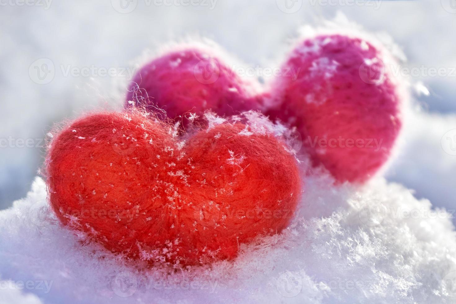 Two wool red and pink hearts standing on the white fluffy snow photo