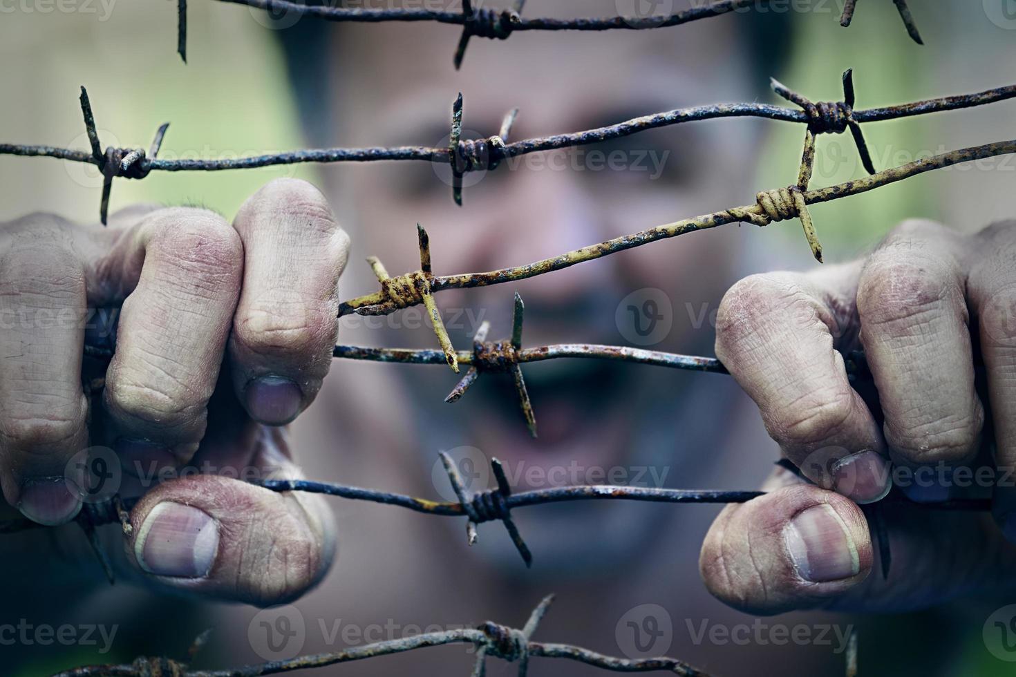 Screaming man trying to break the barbed wire with his hands photo