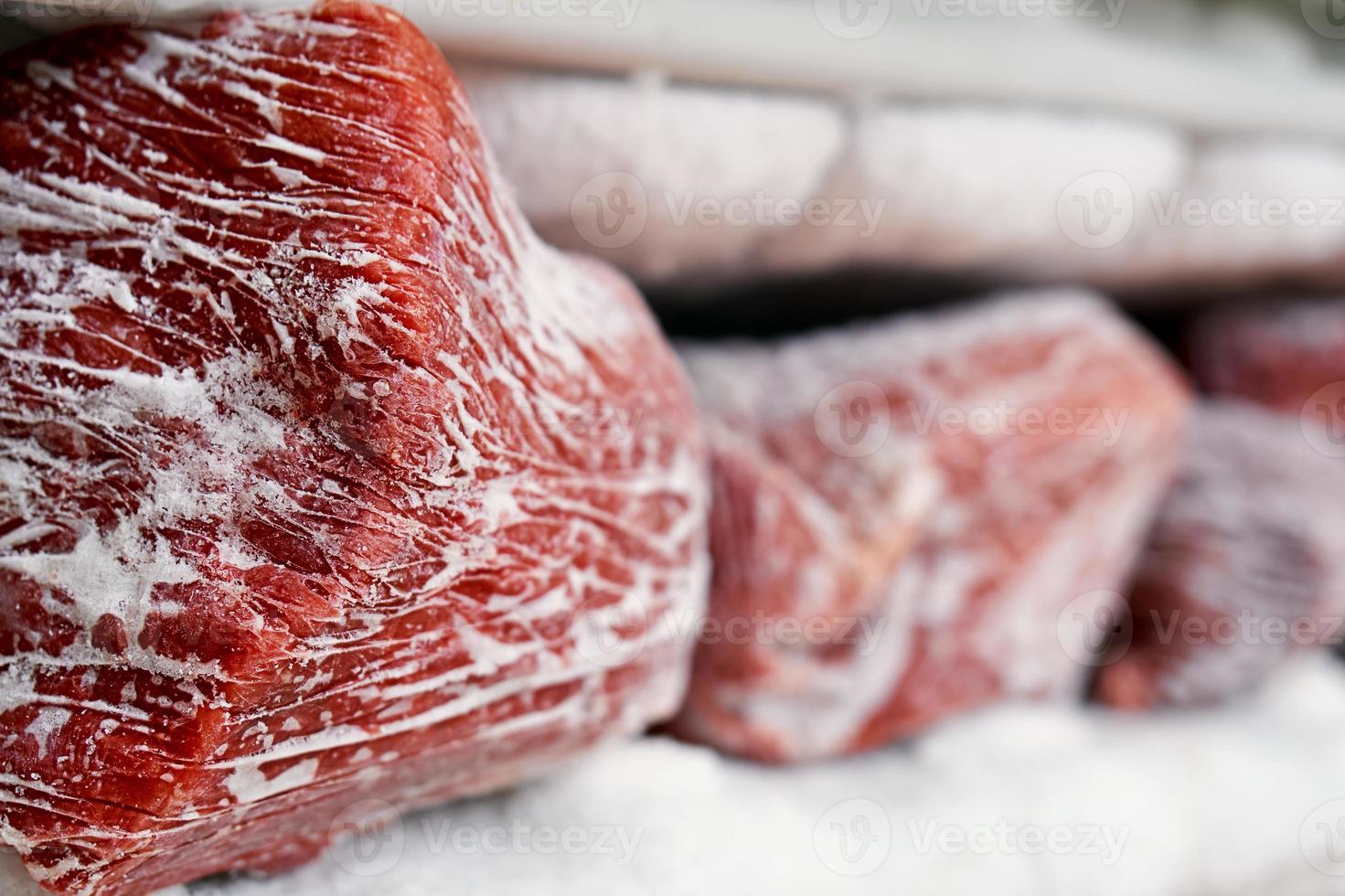 Large pieces of red meat in a freezer with a big quantity of frozen ice and snow photo