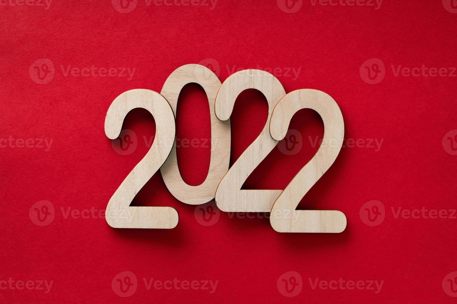 2022 year wooden numbers lying on the red paper background with shadows photo