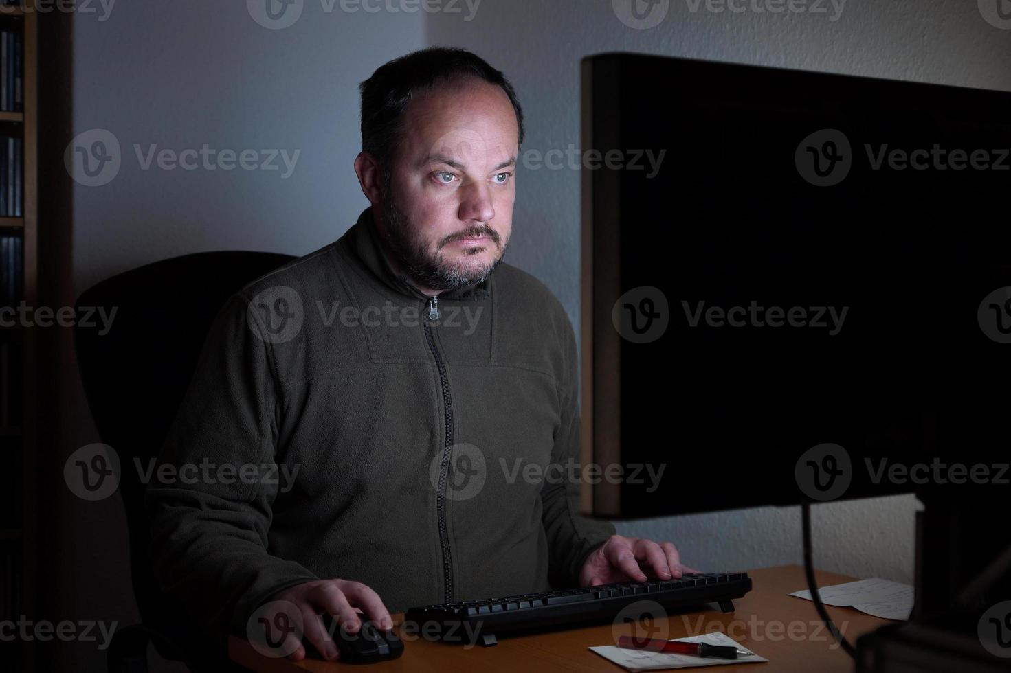 hombre sentado frente a la computadora en la noche foto