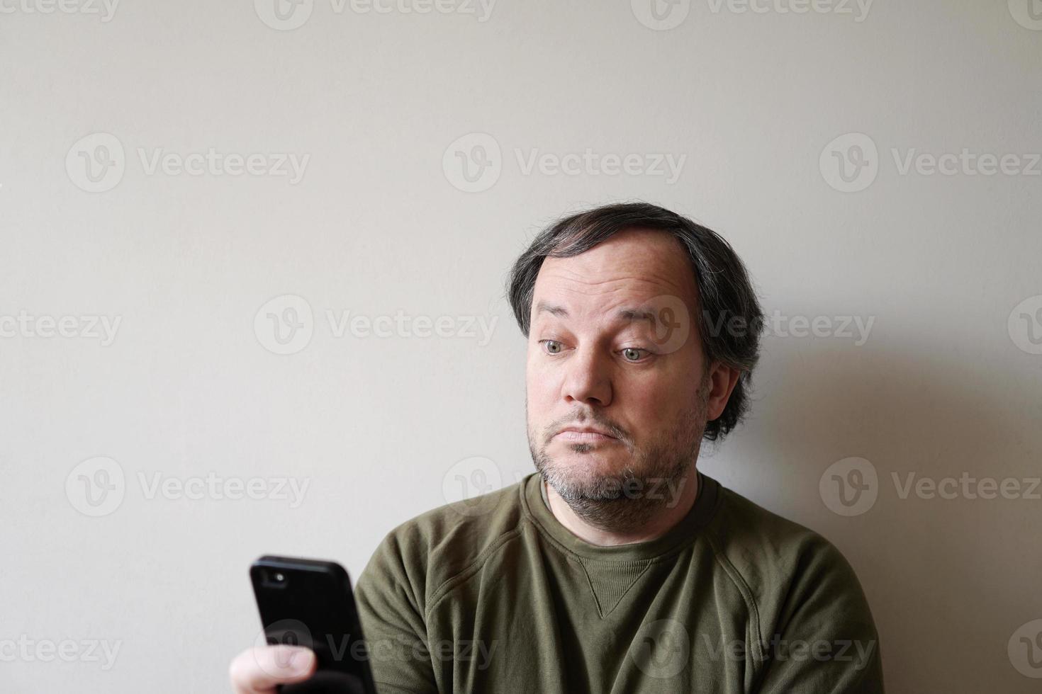 wide-eyed man looking at smartphone photo