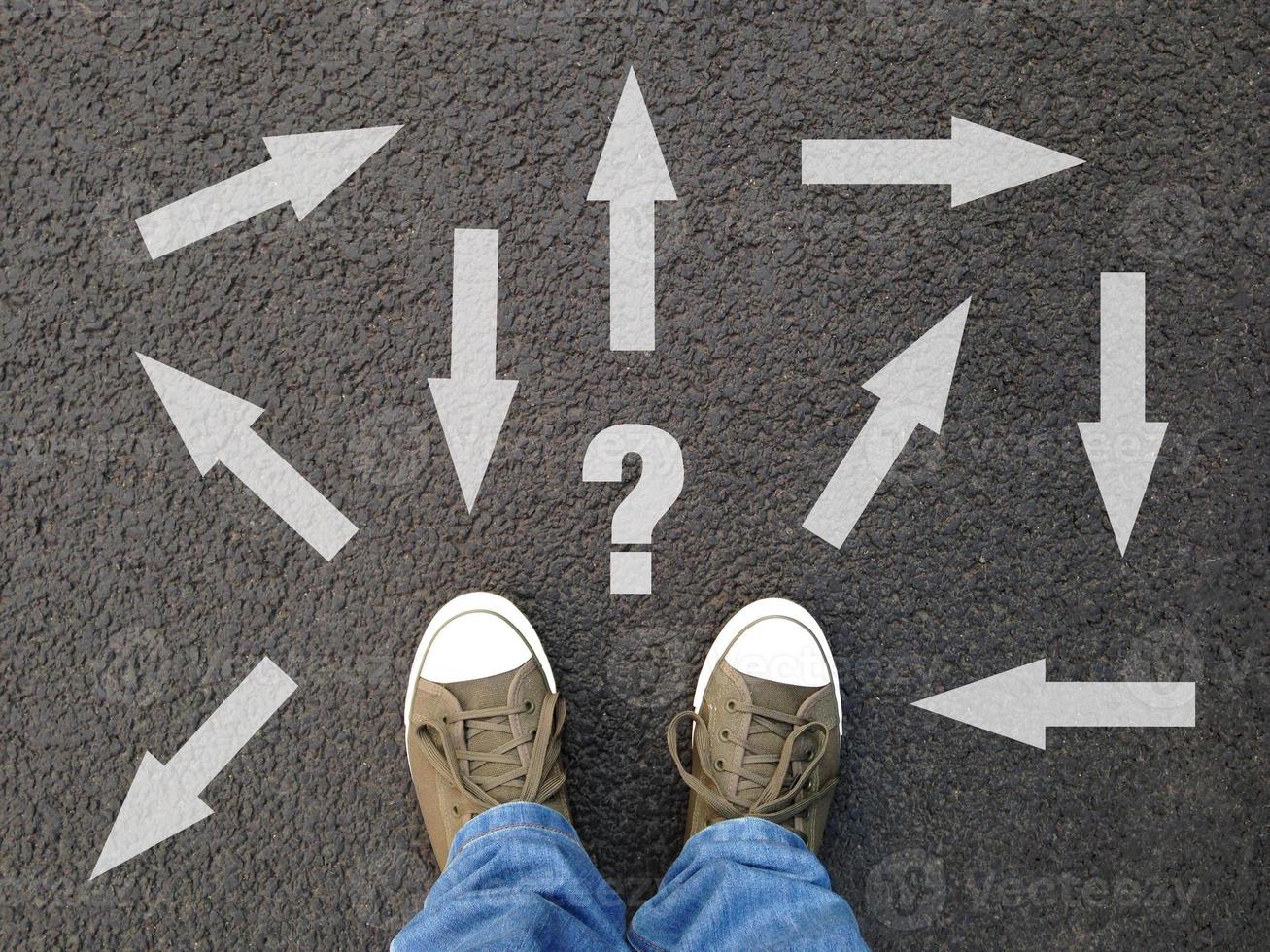 feet standing on asphalt with multitude of arrows in diffrent directions photo
