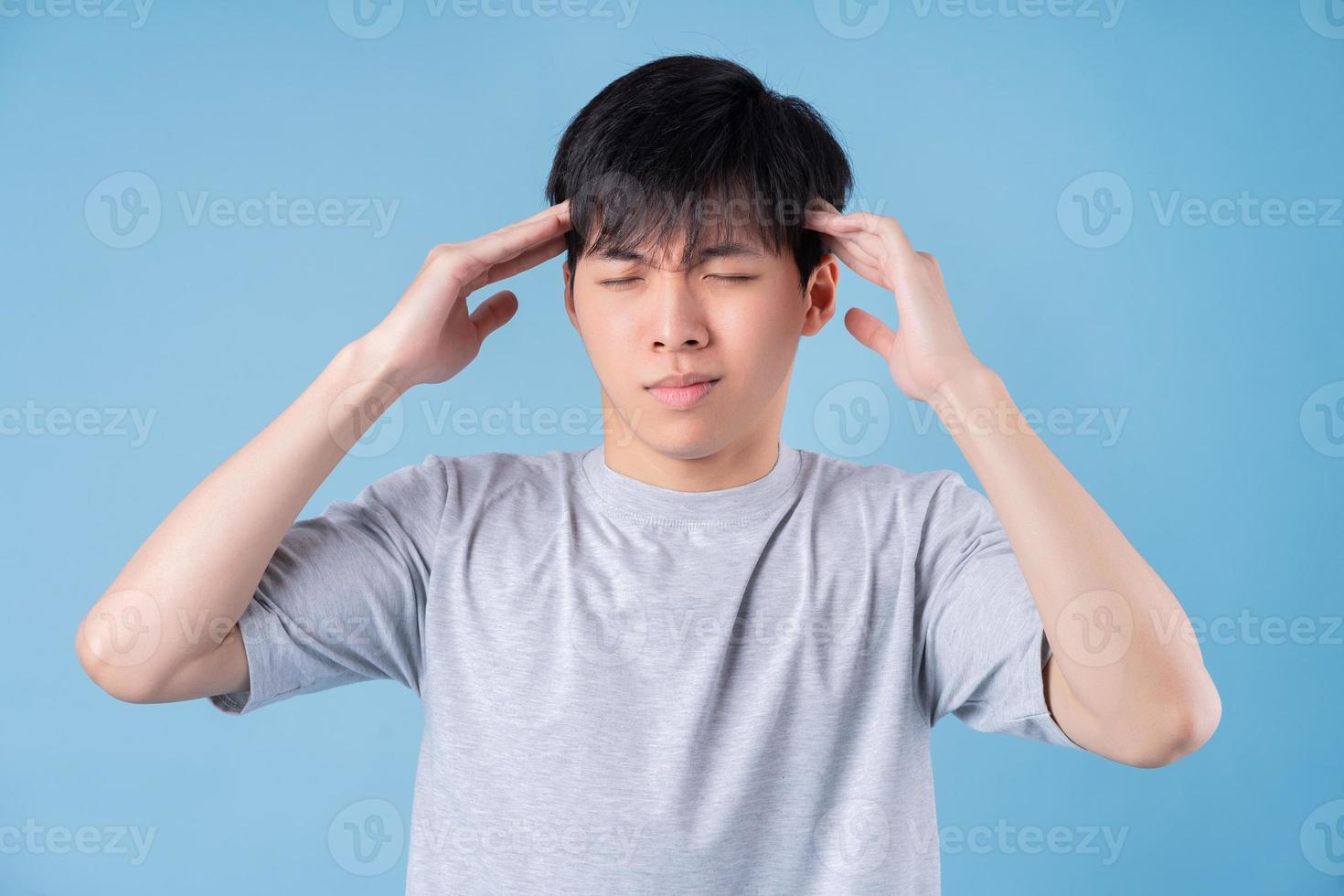 Young Asian man posing on blue background photo