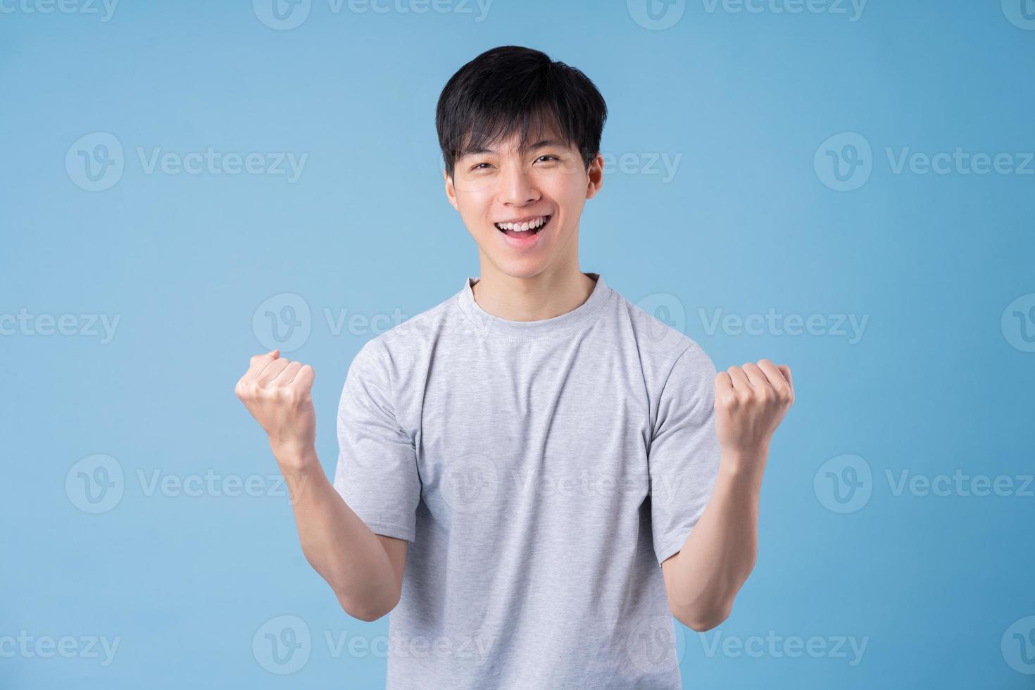 Young Asian man posing on blue background photo